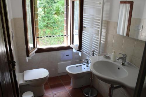 ein Bad mit einem Waschbecken, einem WC und einem Fenster in der Unterkunft Villa Flangini in Asolo