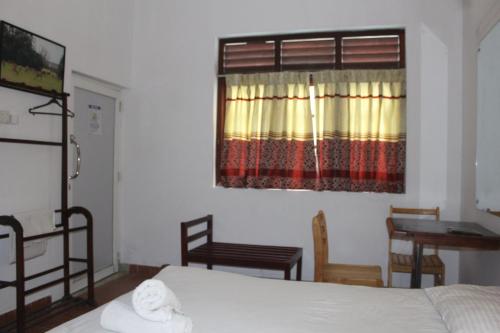 a bedroom with a bed and a desk and a window at Natures Bliss Holidays in Ja-Ela