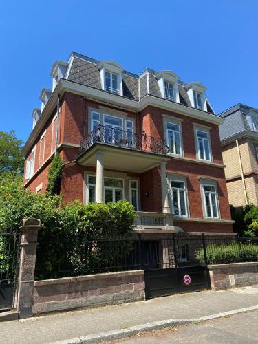 a large red brick house with a balcony at Le Relais de l'Orangerie in Strasbourg