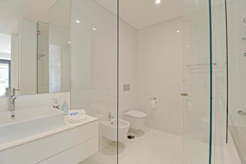 ヴィラモウラにあるWHITE & NATURE APARTMENTの白いバスルーム(トイレ、ガラス張りのシャワー付)