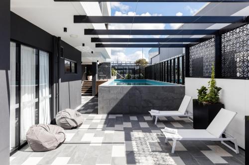 a patio with a pool and two chairs on a building at Quest Robina in Gold Coast