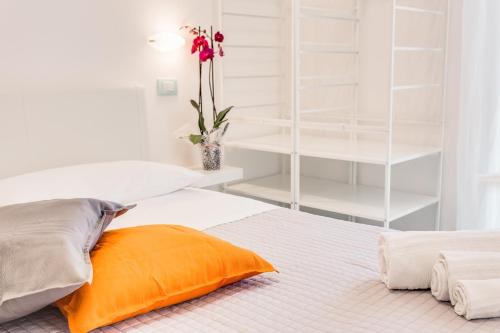 a white bedroom with an orange pillow and white shelves at Mare Home Brunch&Beauty - Adults Only in Cesenatico