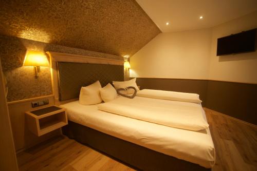 a hotel room with a bed with white sheets at Hotel Schlosskrone in Füssen