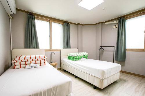 two beds sitting in a room with windows at K Guesthouse in Gangneung