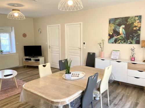 uma sala de estar com uma mesa e cadeiras e uma televisão em Gîte Bambou em Seigy