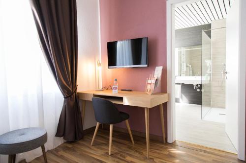 a home office with a desk and a tv on a wall at Enjoy 1313AG Hotel Touring in Chiasso