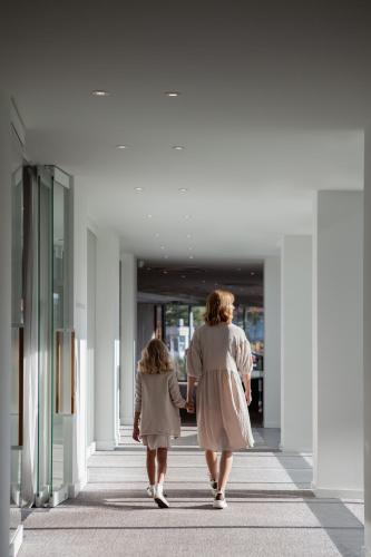 a woman and a child walking down a hallway at Hotel Shuum Boutique - Destigo Hotels in Kołobrzeg