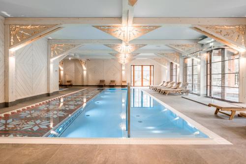 a large pool with blue water in a room with windows at Aries Hotel & SPA Wisła in Wisła