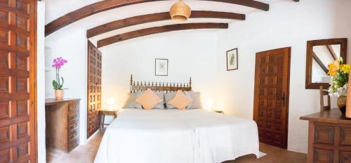 a bedroom with a white bed with a wooden ceiling at Casa Napsu in Mijas