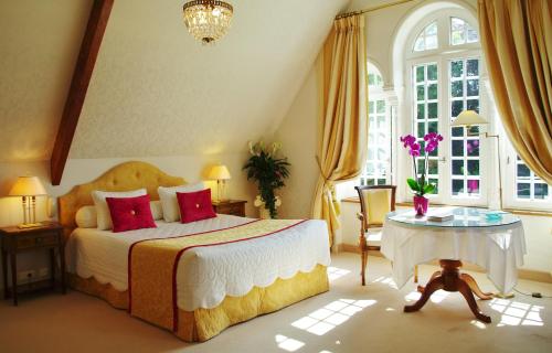 a bedroom with a bed and a table and windows at Manoir De Kertalg in Moëlan-sur-Mer