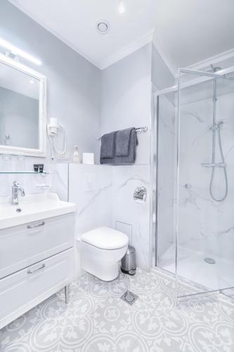 a white bathroom with a toilet and a shower at Forums Boutique Hotel in Rīga