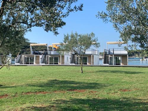 a house on the water with a lawn and trees at Floating House - ARENA 2 in Pula