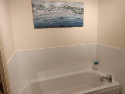 uma casa de banho com banheira e uma pintura na parede em River Ground Floor Apartment - 70 Skipper Way em Saint Neots