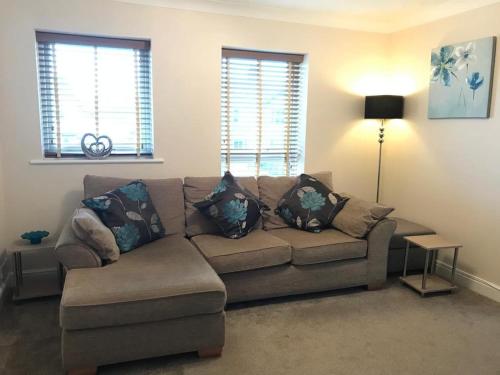 a living room with a couch and two windows at Eaton Ford Green Apartment in Saint Neots