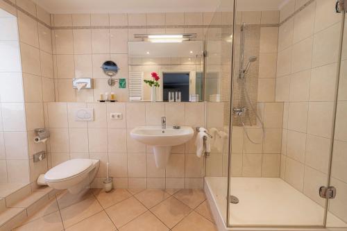 a bathroom with a toilet and a sink and a shower at Strandhotel Fontana in Timmendorfer Strand