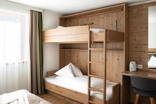 a bunk bed in a room with a desk and a bed at Pension Patricia in Kaprun