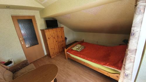 a small bedroom with a red bed and a couch at Agroturystyka Domki Eden in Sarbinowo