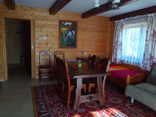 a dining room with a table and a couch at Świerkowe Chatki - Apartament Kominkowy in Olchowiec