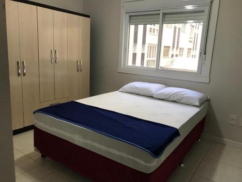 a bed in a room with a window at Ed Gustavo in Capão da Canoa