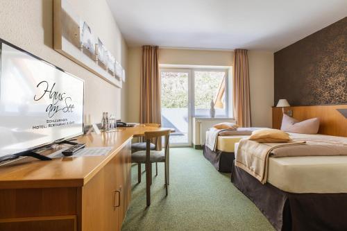a hotel room with two beds and a desk at WAGNERS Seehotel Schleusingen in Schleusingen