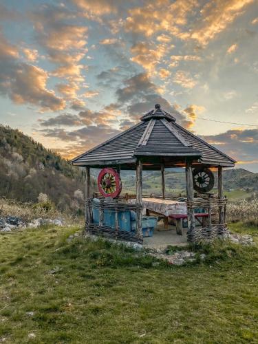 a wooden gazebo with a bench in a field at Log cabin Uvac (Vikendica Saponjic) in Nova Varoš