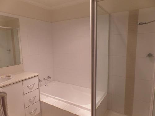 a white bathroom with a shower and a sink at Travers Street Apartment in Wagga Wagga