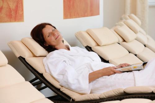 a woman laying in a reclining chair with a wii remote at Hotel Schlosskrone in Füssen