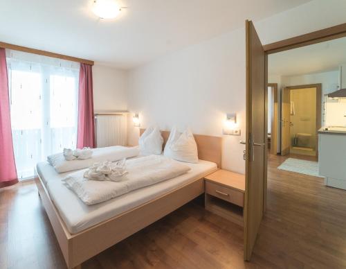 a bedroom with a bed with white sheets and a window at Residence Ortlerhof in Prato allo Stelvio