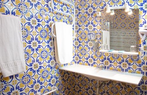 baño azul y blanco con lavabo y espejo en Rainha Santa Isabel - Óbidos History Hotel, en Óbidos