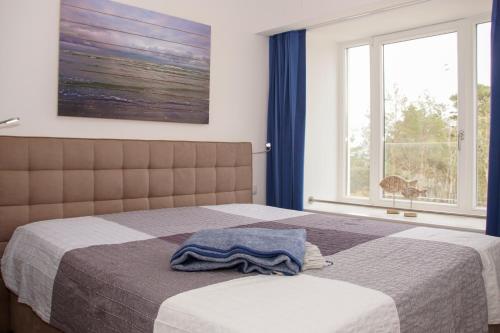 ein Schlafzimmer mit einem Bett mit einer Decke und einem Fenster in der Unterkunft FeWo Prora - MeerSonneWind in Binz