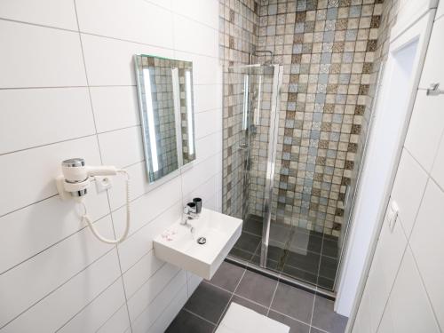 y baño con lavabo y ducha. en Kaštieľ Penzion, en Rimavská Sobota