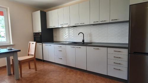 een keuken met witte kasten, een wastafel en een tafel bij DoTleń Villa in Tleń