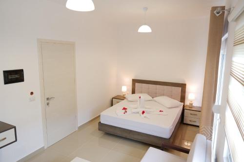 a bedroom with a white bed with red flowers on it at Fabeno Villa in Sarandë