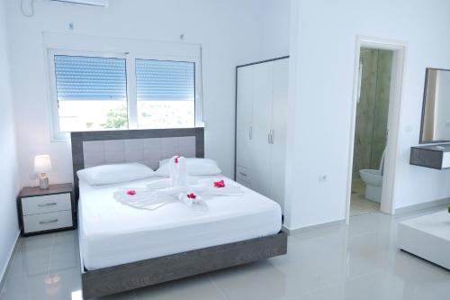 a bedroom with a white bed with flowers on it at Fabeno Villa in Sarandë