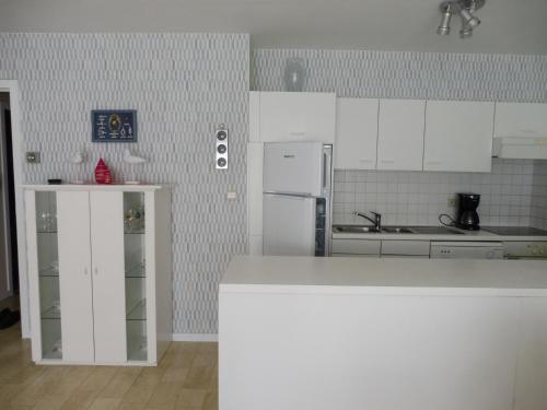 a kitchen with white cabinets and a white refrigerator at Gabbiano De witte meeuw in Koksijde