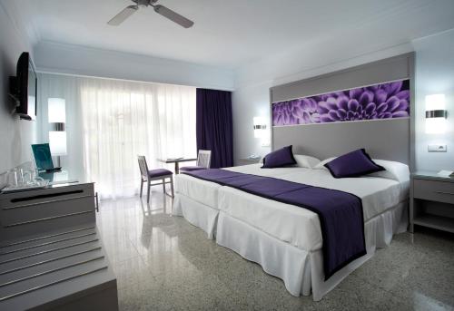 a bedroom with a large bed with a purple painting on the wall at Hotel Riu Nautilus - Adults Only in Torremolinos