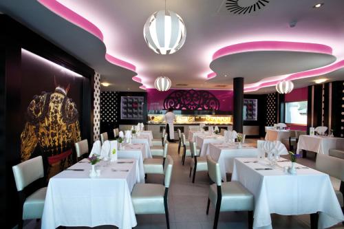 a restaurant with white tables and chairs and pink ceilings at Hotel Riu Nautilus - Adults Only in Torremolinos