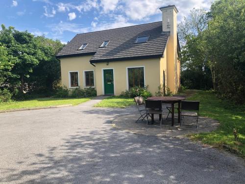 a table and chairs in front of a house at Letterfrack Farm Lodge house in Letterfrack village Connemara in Letterfrack