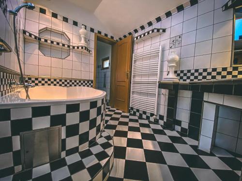 a bathroom with a tub and a checkered floor at Resort Svět in Úžice