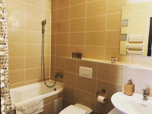 een badkamer met een toilet, een wastafel en een bad bij Tampa Gardens Apartment in Braşov