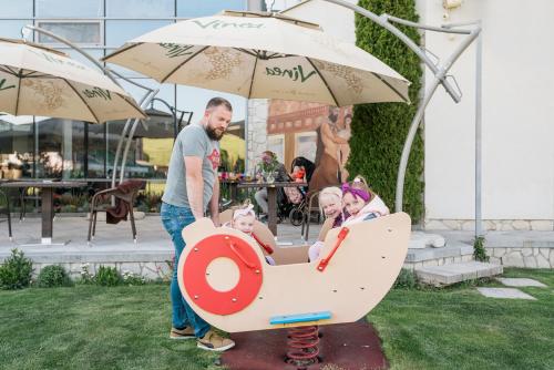 a man and two children playing in a toy car at Penzion Troja in Lipany