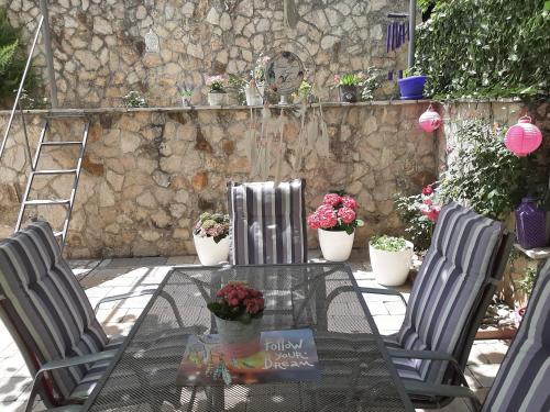 a glass table with chairs and potted plants on a patio at Apartman Miletic in Mostar