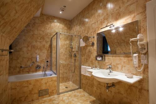 La salle de bains est pourvue d'une douche, d'un lavabo et d'une baignoire. dans l'établissement Tyn Yard Residence, à Prague