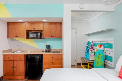 a kitchen with wooden cabinets and a black refrigerator at Beachside Hotel & Suites Cocoa Beach - Port Canaveral in Cocoa Beach