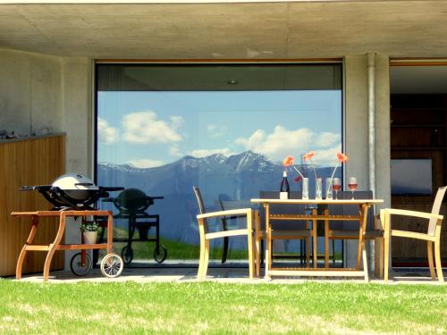 a patio with a table and chairs and a grill at Casa Admisa, spektakuläre Aussicht, Ski in and out, hochwertige Einrichtung, Valserstein und Eiche in Flims