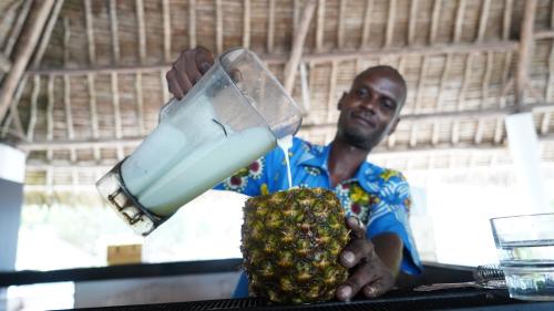 a man is holding a bottle of fruit at Papillon Lagoon Reef Hotel in Diani Beach