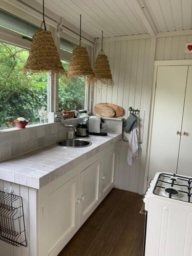 a kitchen with white cabinets and a sink and a window at Het Schulpje in Egmond-Binnen