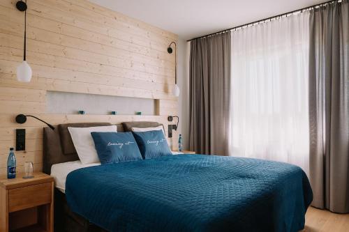 - une chambre avec un lit doté d'une couette bleue et d'une fenêtre dans l'établissement Royal Baltic Apartments, à Darłówko