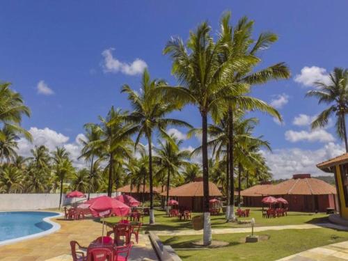 伊列烏斯的住宿－Pousada E Restaurante Doce Desejo，一个带游泳池和桌子以及棕榈树的度假村