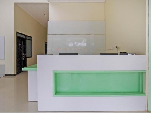 a lobby with a large white counter with a green at OYO 2753 Irma's Residence in Blitar
